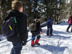alumne invident caminant sobre de la neu amb l'ajuda de la barra direccional